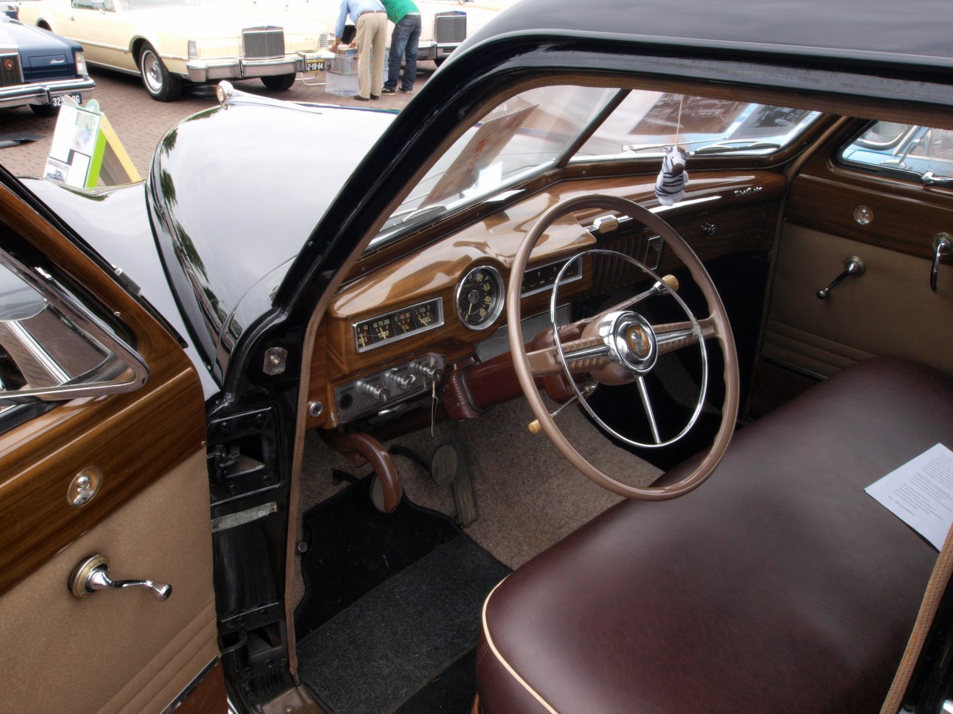 Vintage car interior with wooden dashboard, bench seat, and retro steering wheel.