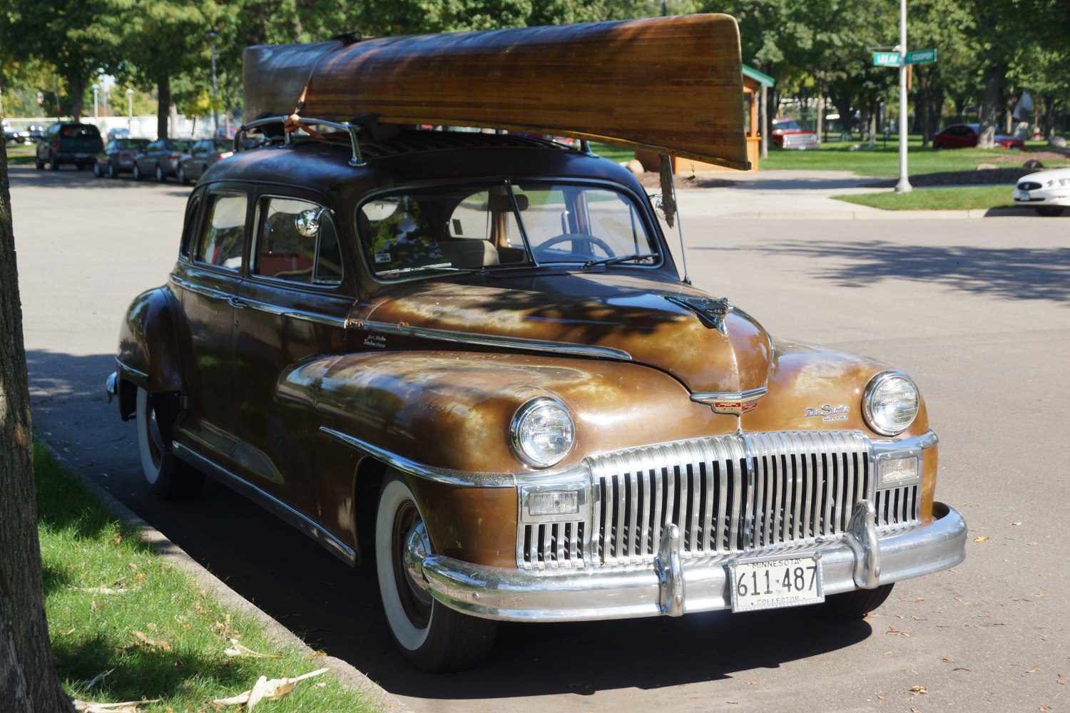 Vintage car front with large vertical grille and wooden canoe roof rack