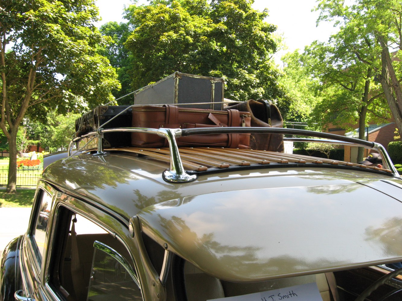 Wooden slat roof rack with vintage luggage on classic car roof