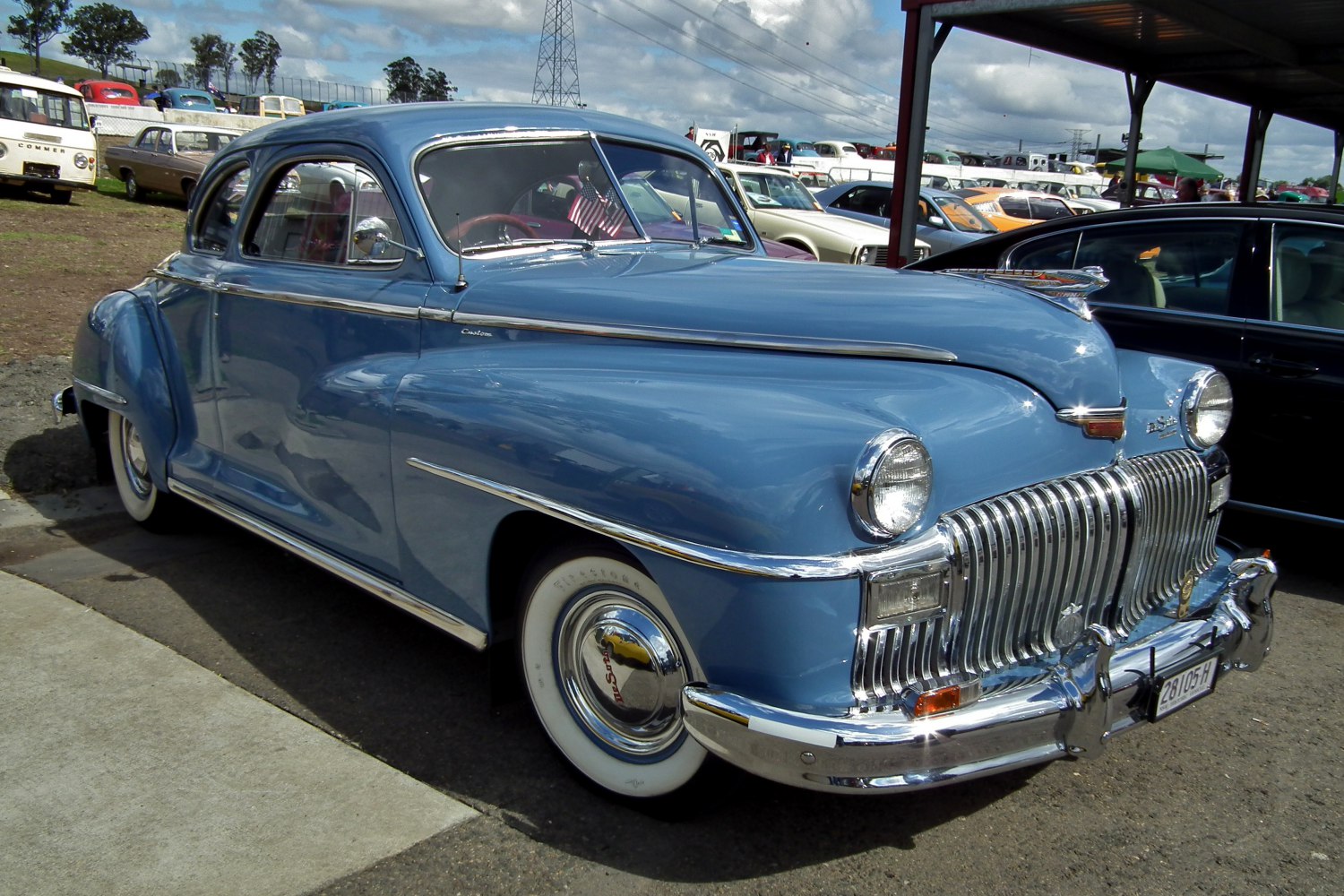 Blue vintage coupe with chrome grille and whitewall tires