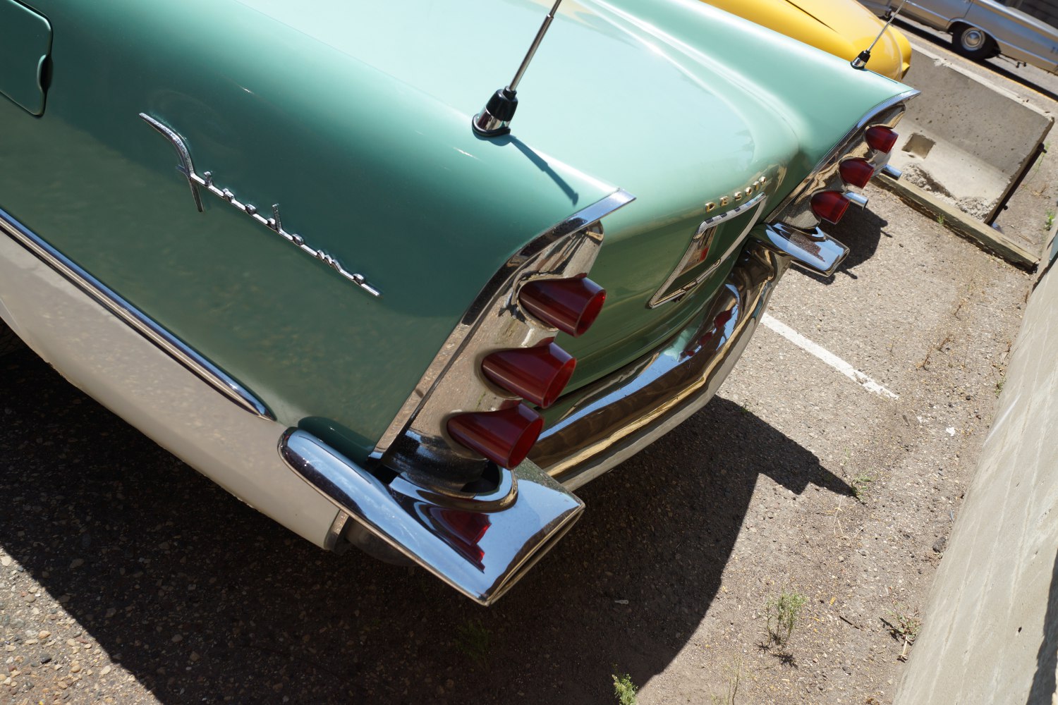 Close-up of retro tail lights and large chrome bumper on classic sedan.