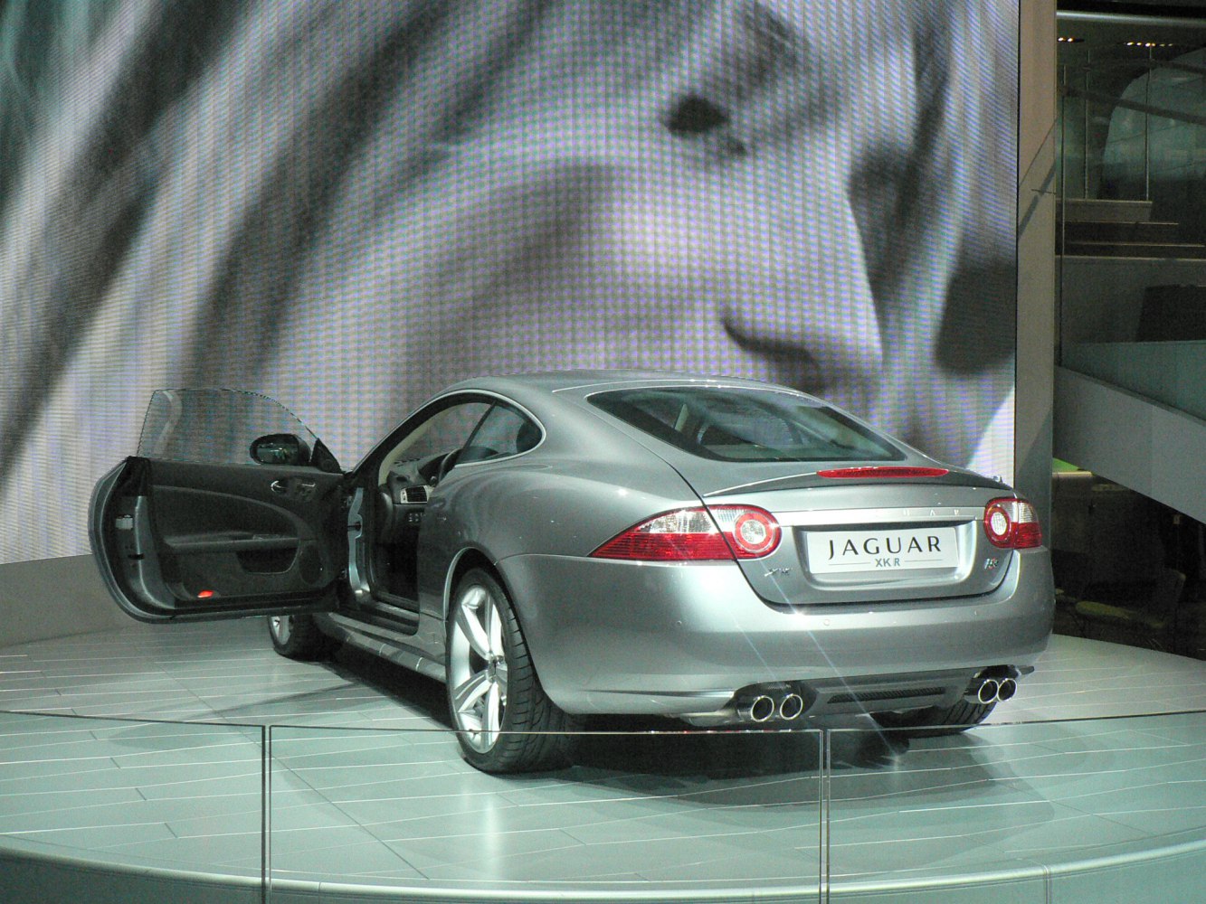 Rear view of coupe with round taillights, quad exhaust, open driver door