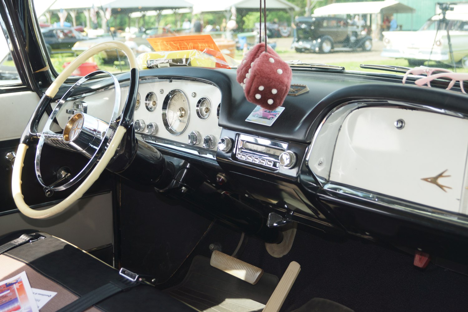 Vintage car dashboard with steering wheel and fuzzy dice