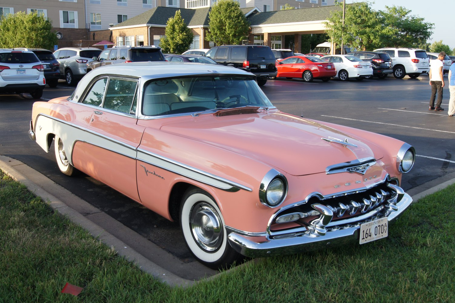 Two-tone pink and white classic coupe with chrome grille and whitewall tires