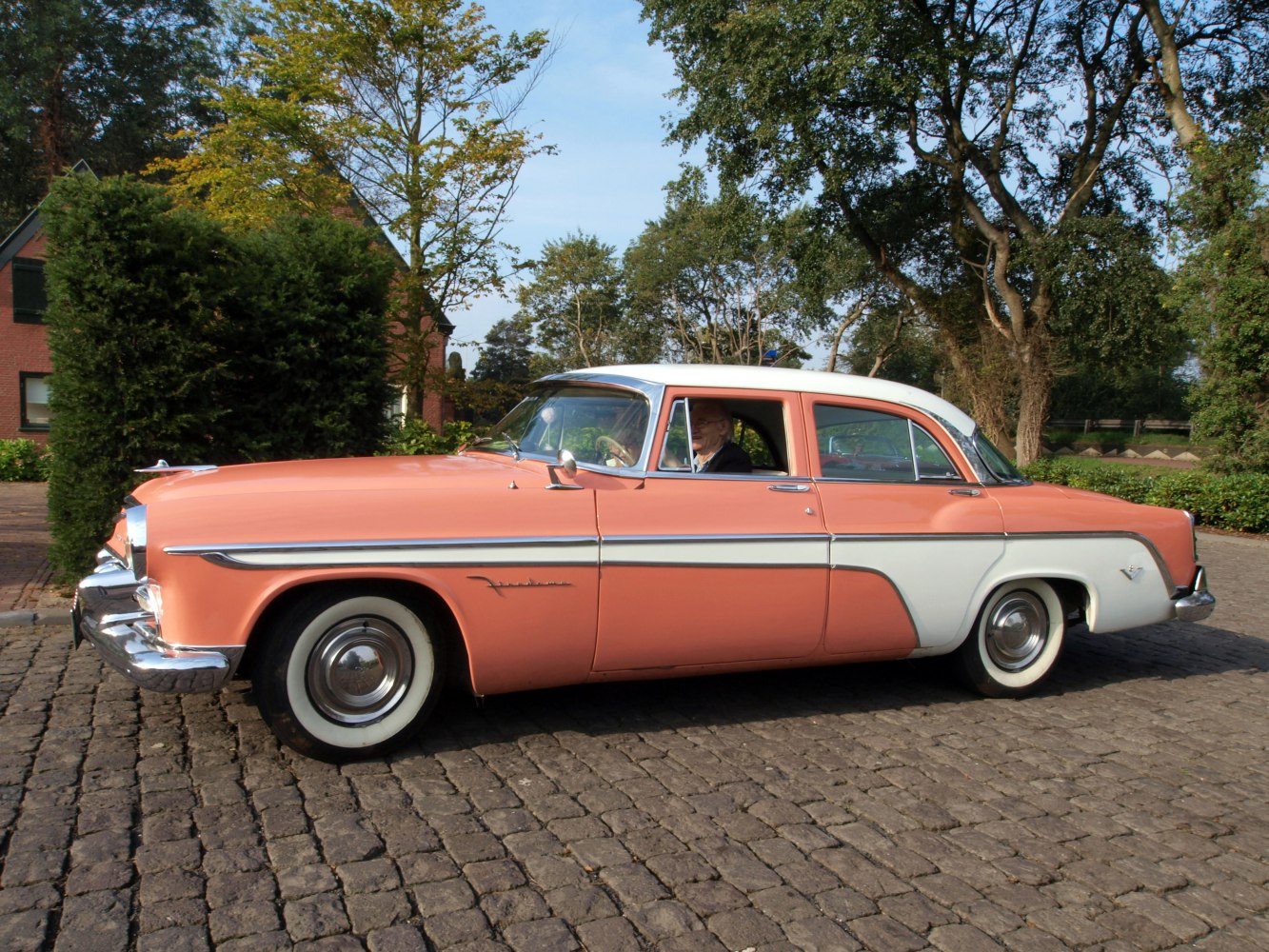 Two-tone four-door vintage sedan with chrome trim and whitewall tires
