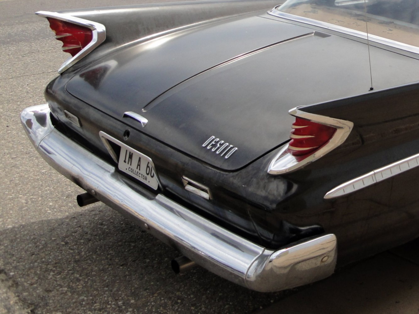 Distinctive tail fins and chrome bumper on classic vintage car rear.