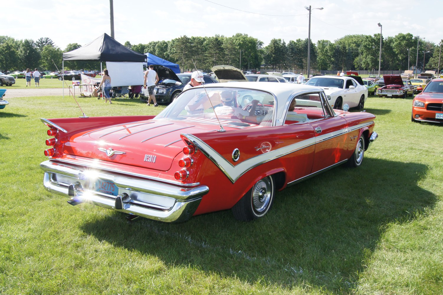 Red 1950s two-door coupe with rear tail fins and chrome bumper