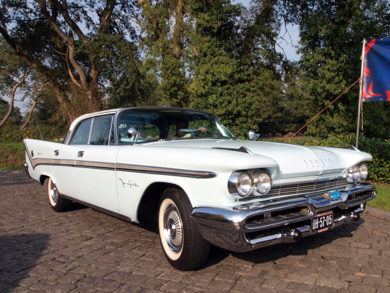 Dual round headlights, chrome grille, tailfins, white classic sedan