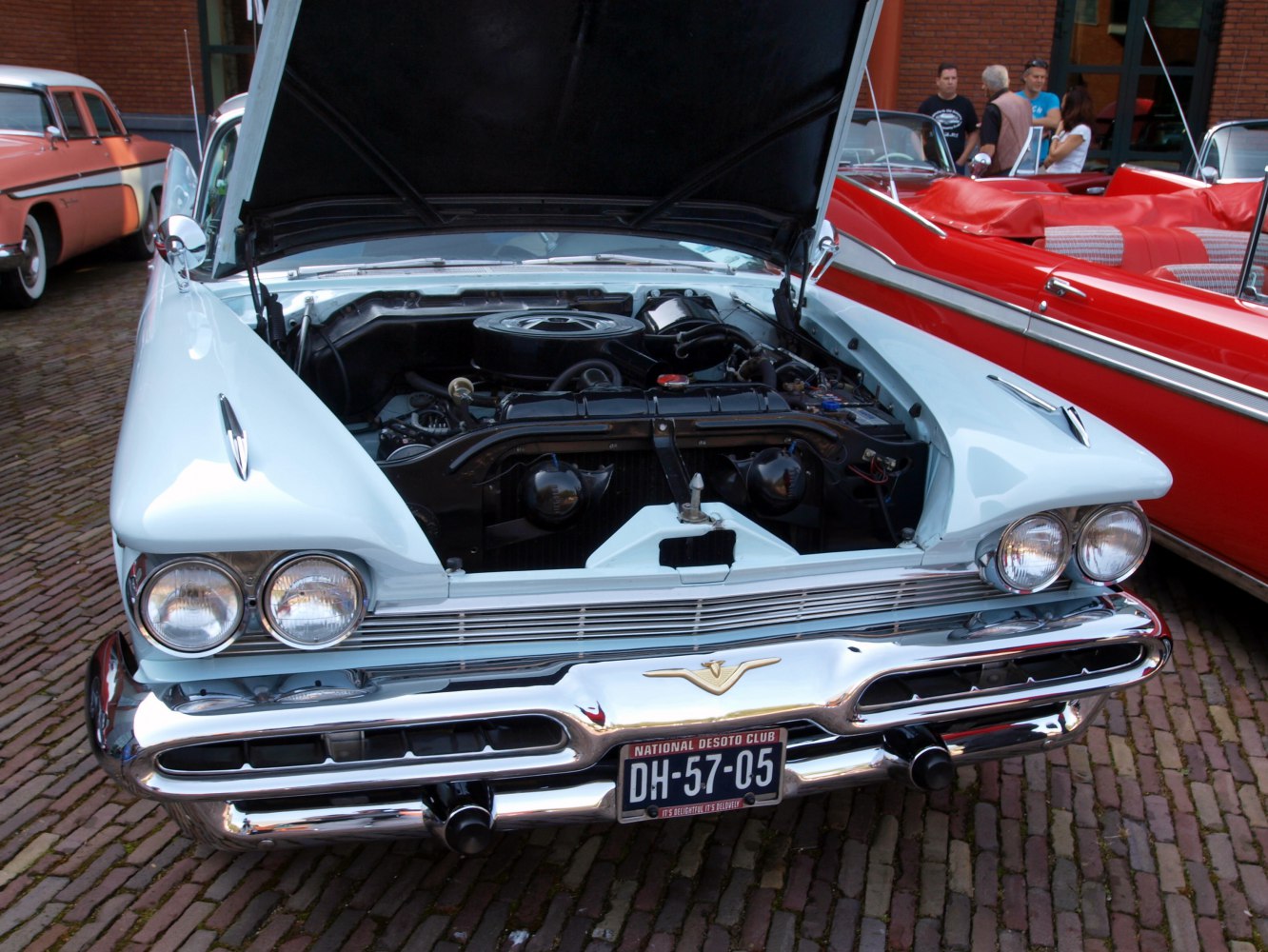 Front view with open hood revealing engine bay and dual round headlights.