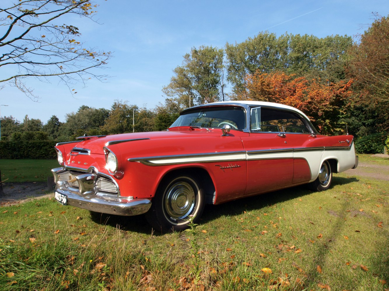 Two-tone red and white vintage sedan with chrome trim and classic 1950s design