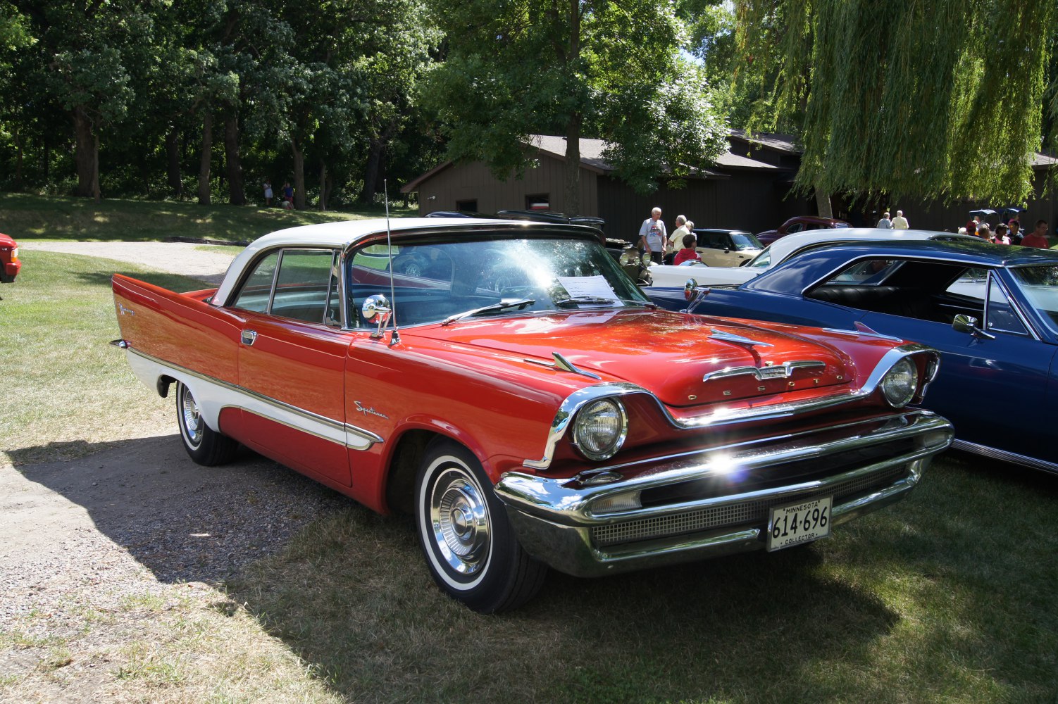 Red two-door classic car with white roof and prominent chrome details