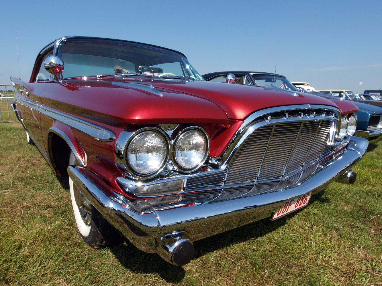 Dual round headlights and large chrome grille on vintage metallic red car