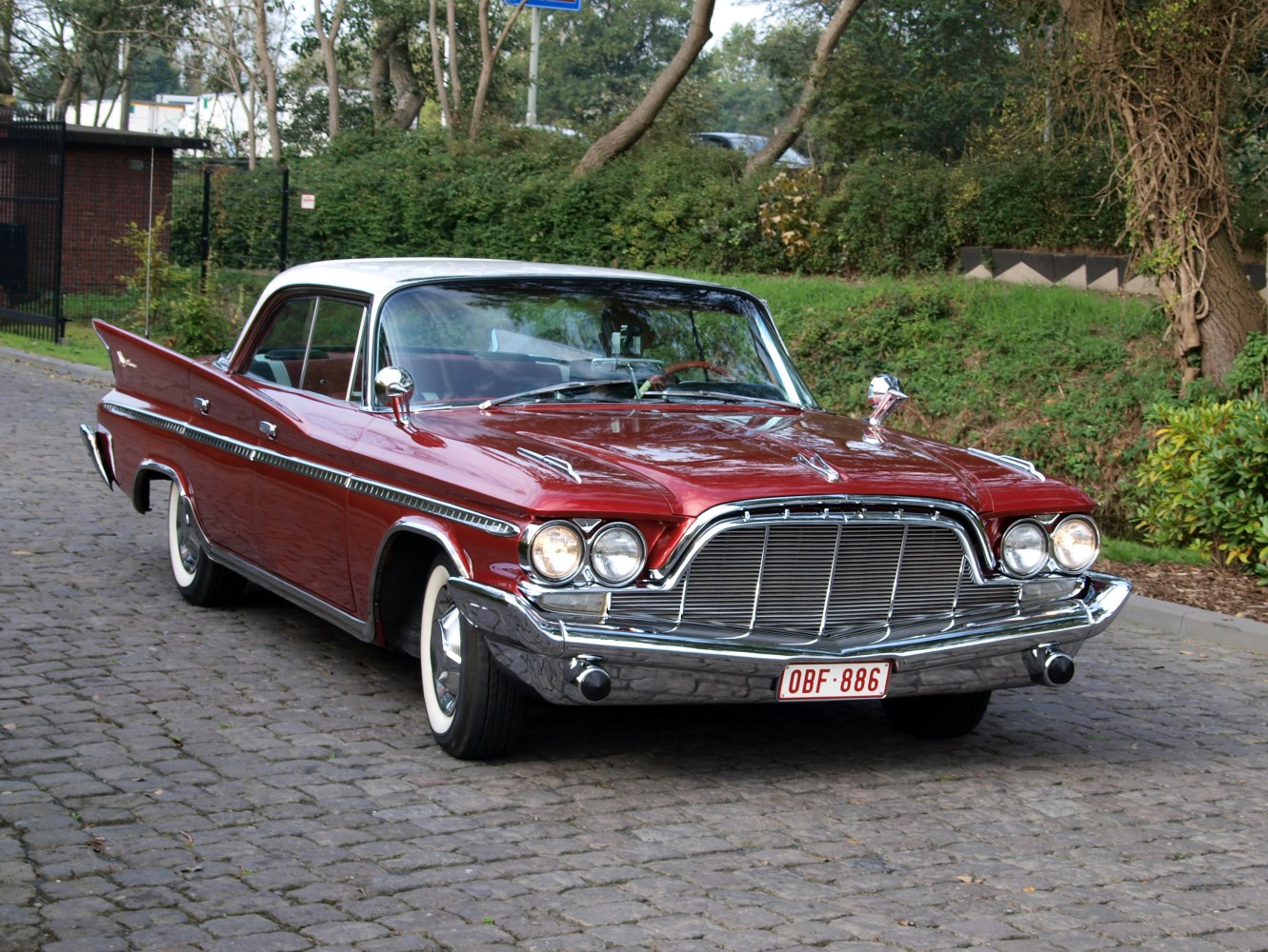 Classic front grille and dual round headlights on a vintage 4-door hardtop with car fins.