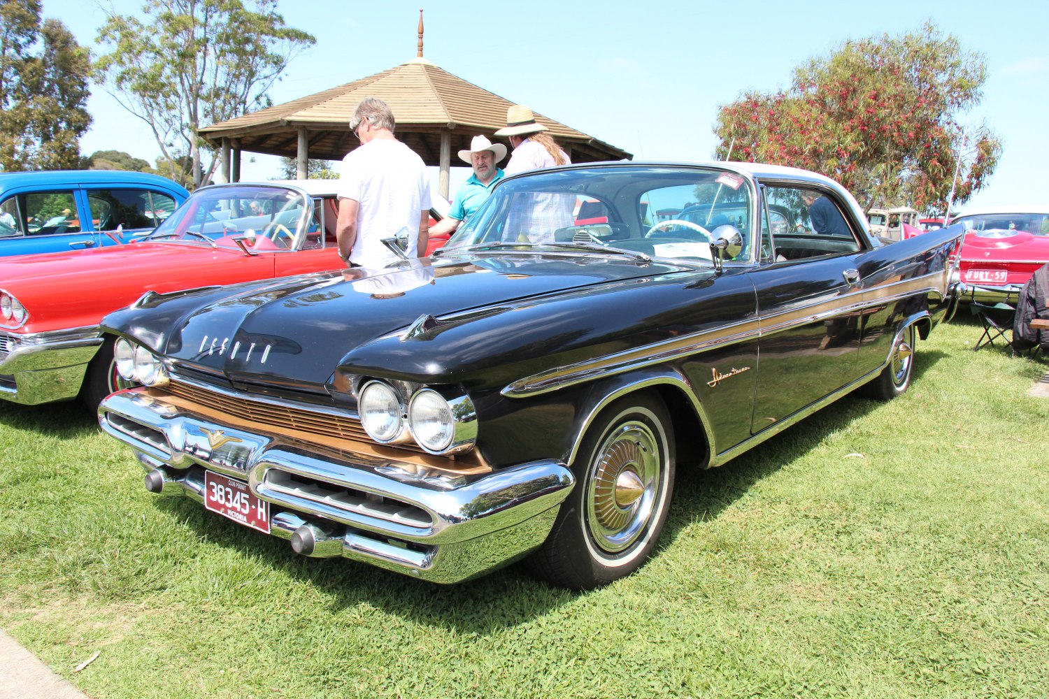 Dual headlights, prominent chrome bumper, and large tailfins on a classic coupe.