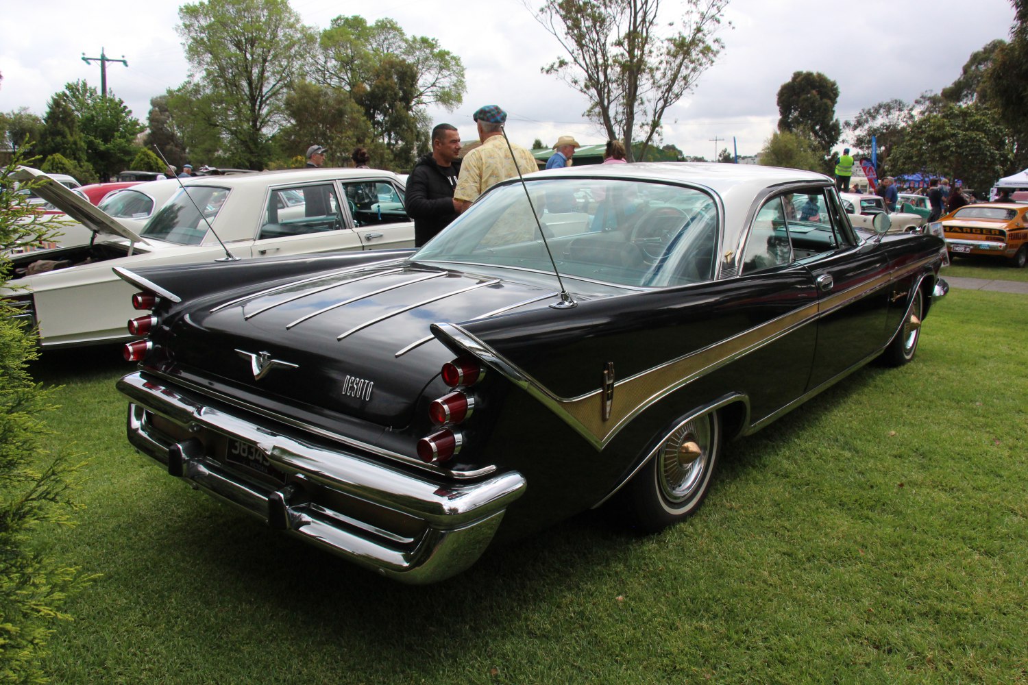 Rear view of vintage coupe with distinctive tailfins and triple stacked round taillights.