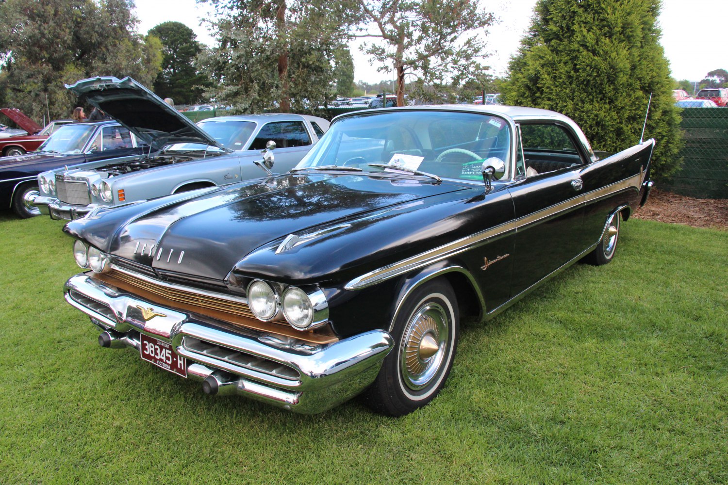 Dual round headlights, chrome grille, two-tone coupe with rear fins
