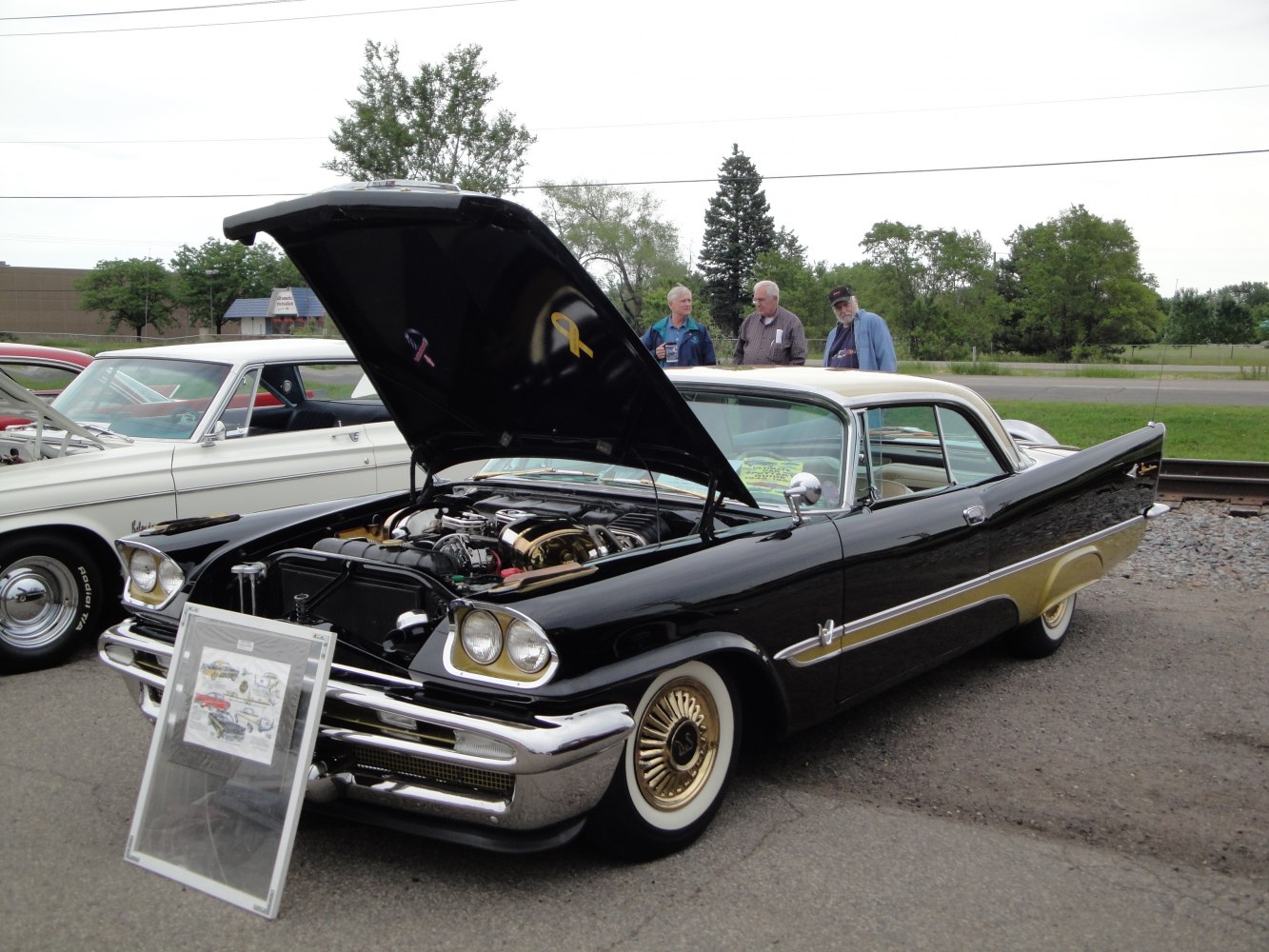 Classic 1950s coupe with open hood and tail fins