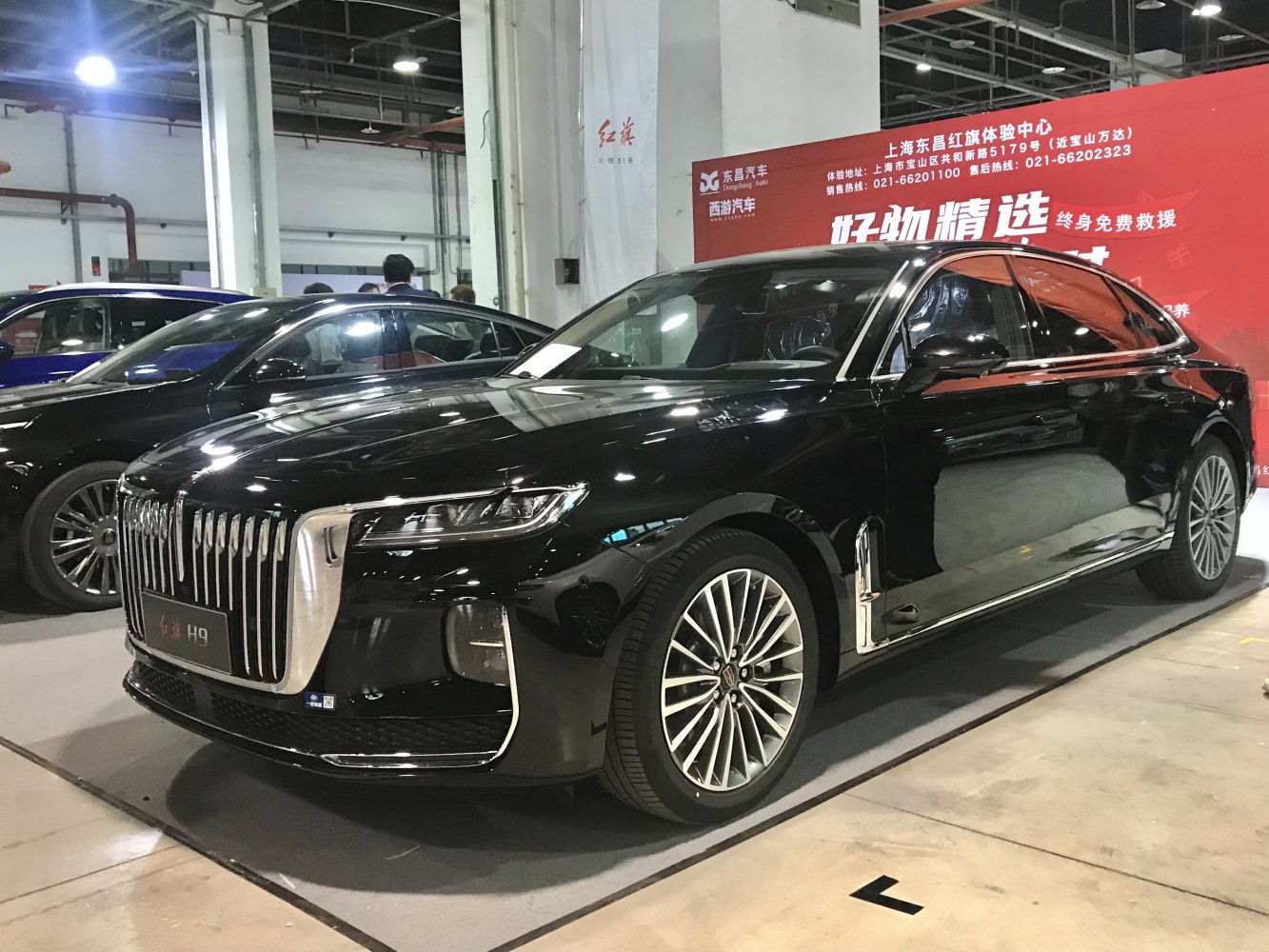 Luxury black sedan with prominent vertical chrome grille and multi-spoke wheels