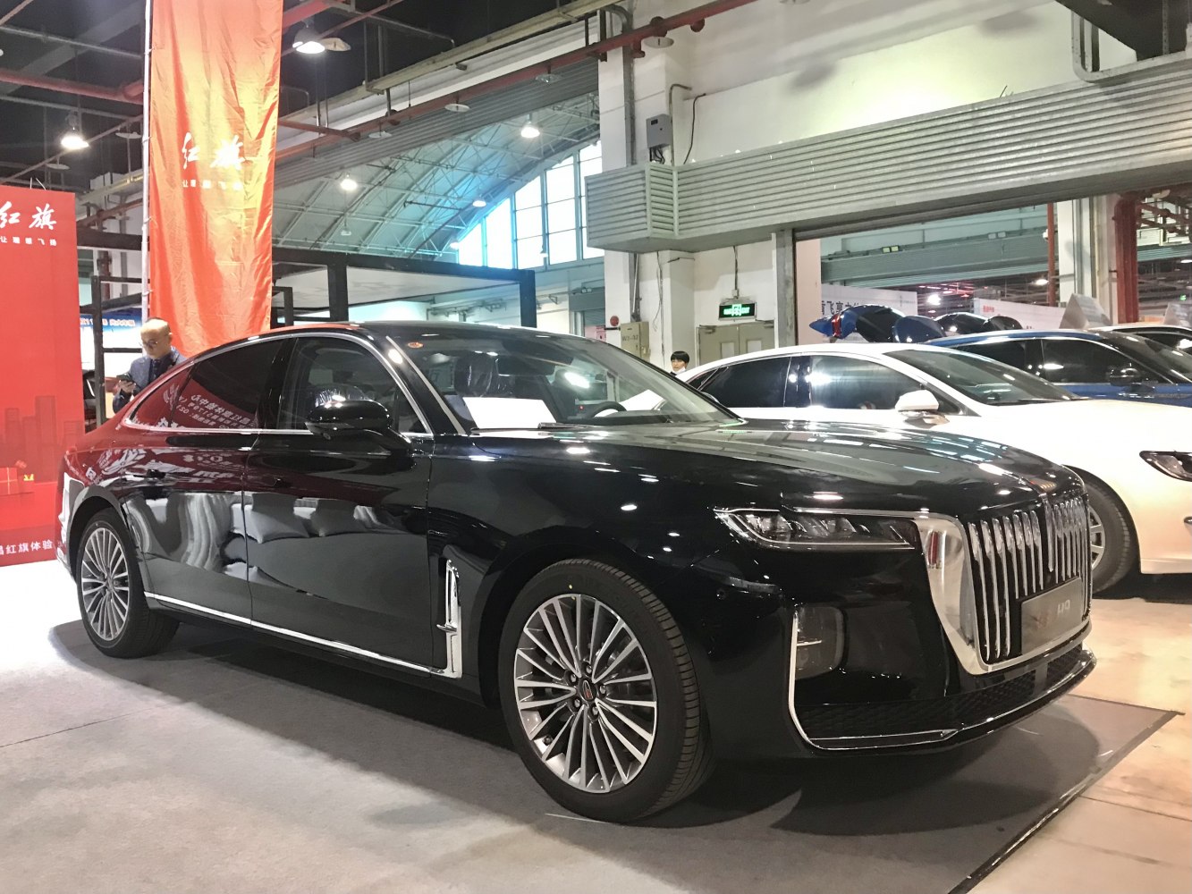 Black luxury sedan with vertical chrome grille and multi-spoke alloy wheels