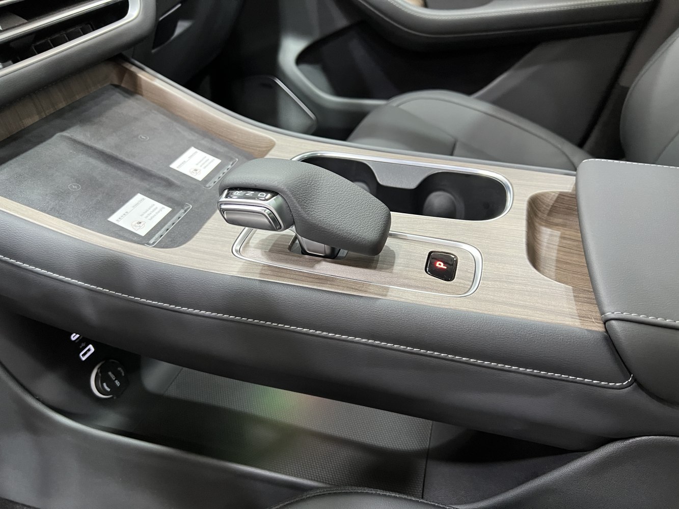 Center console with gear shift lever, wood trim, cup holder, leather stitching