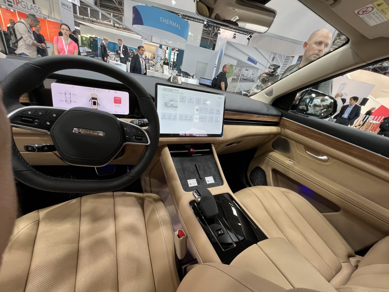 Beige leather seats with wood trim and dual digital displays in a modern vehicle interior