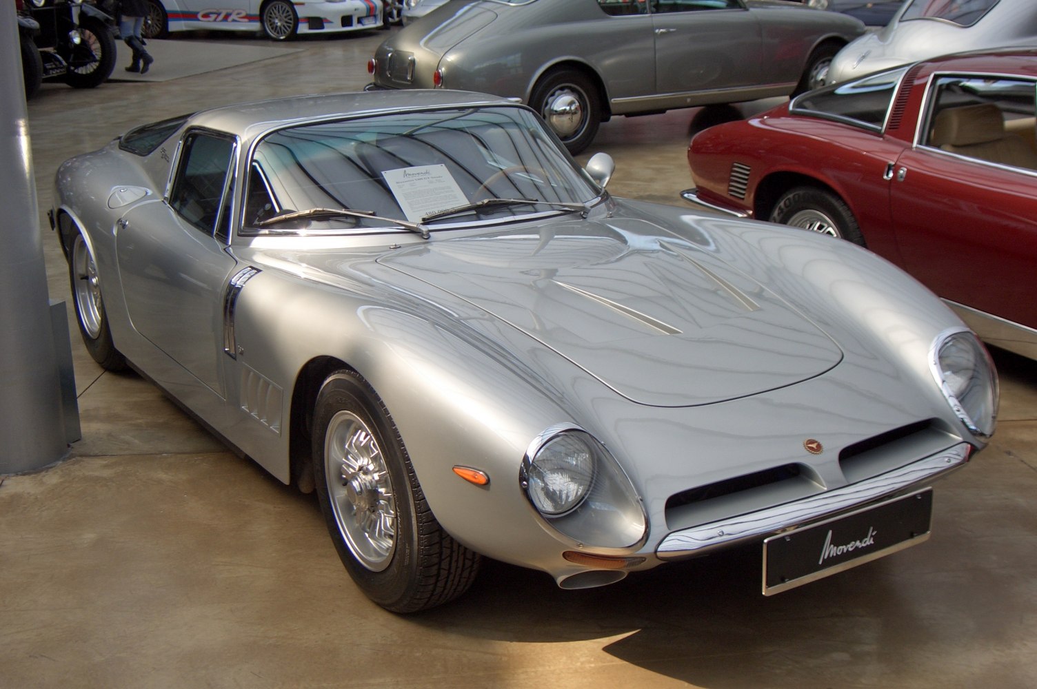 Silver aerodynamic sports car with round headlights and classic curves
