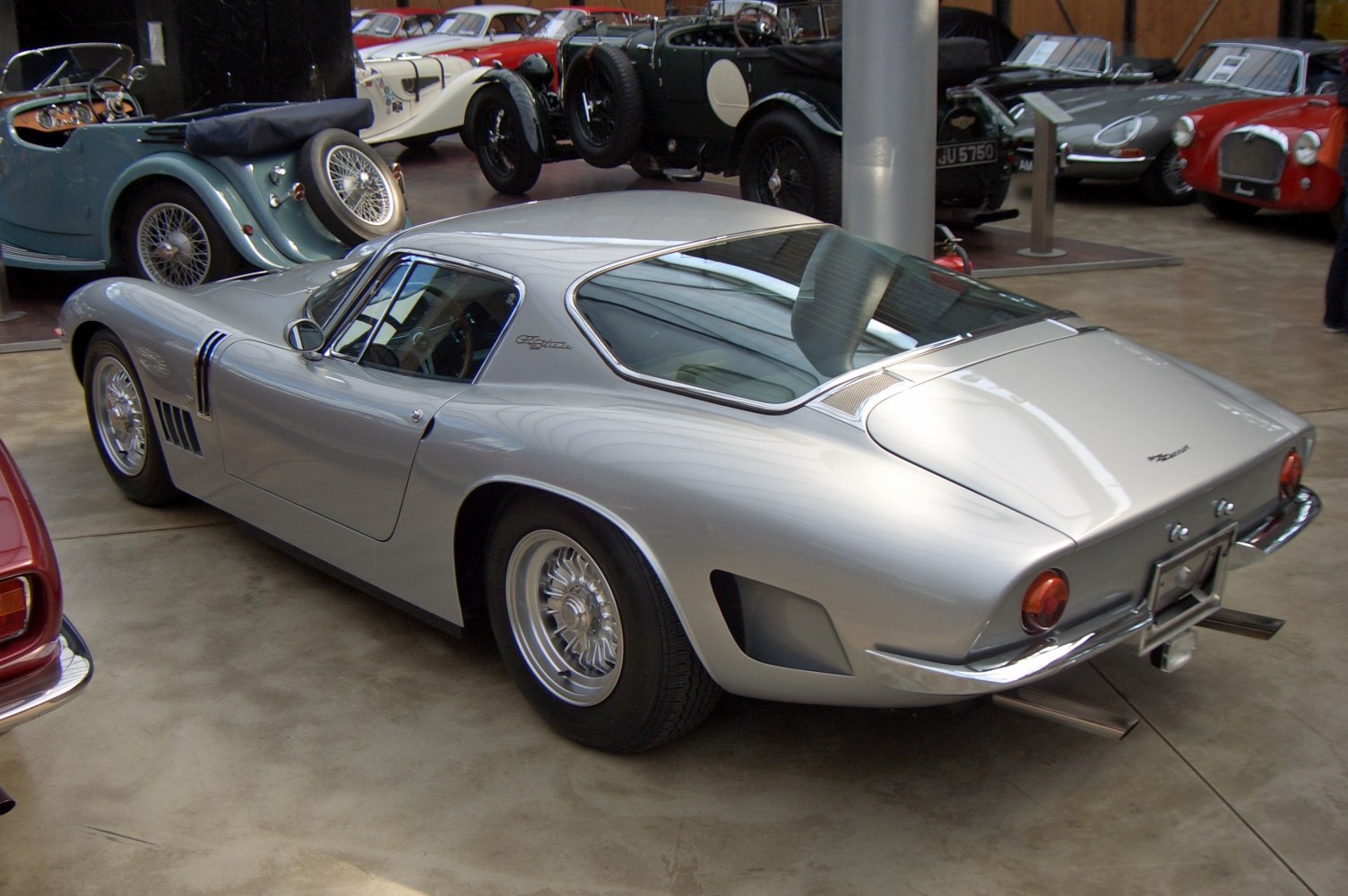Silver classic coupe rear side view with exposed rear exhausts and distinctive vents