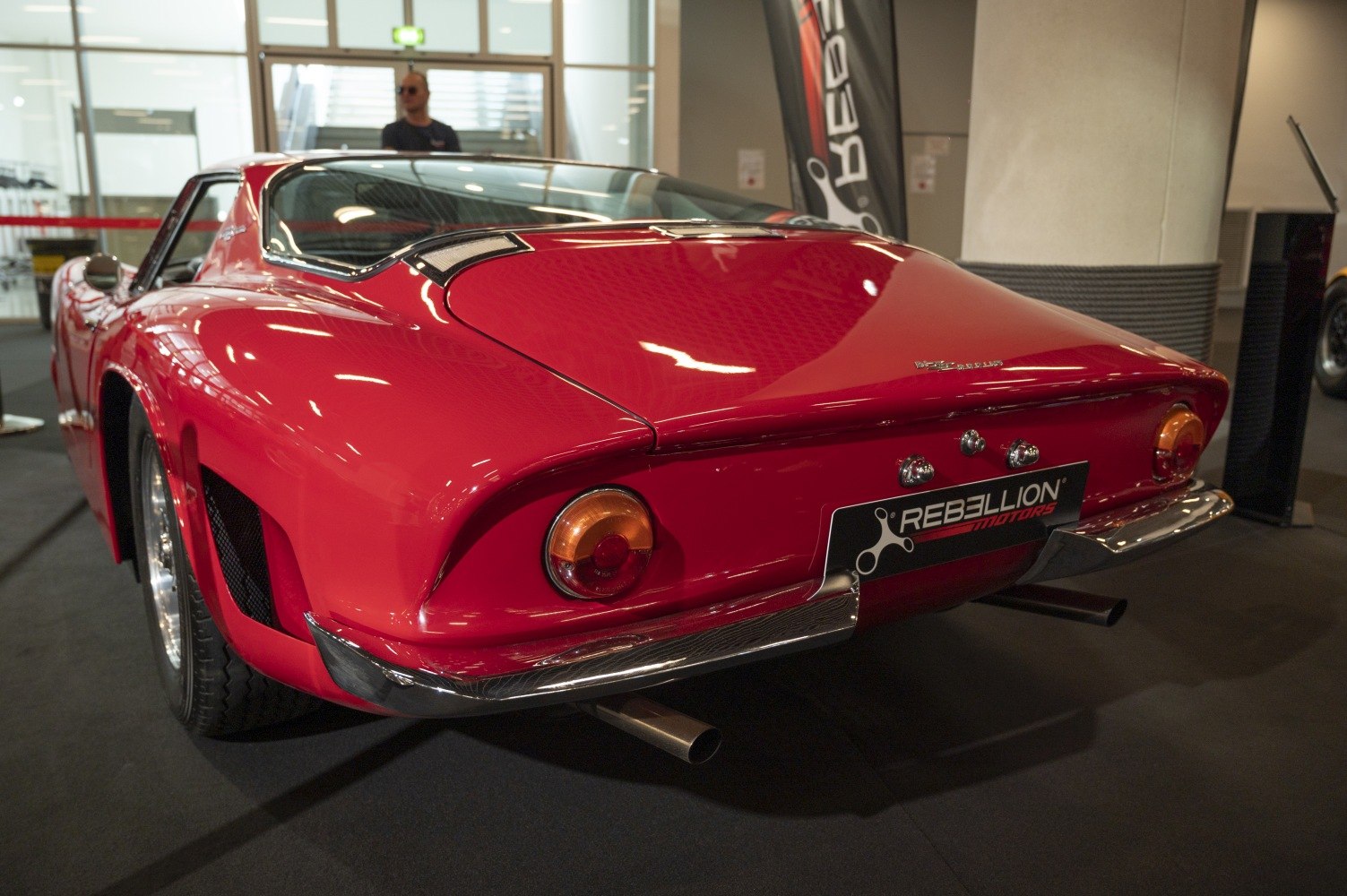 Classic 1960s sports car rear with round tail lights and dual exhaust pipes