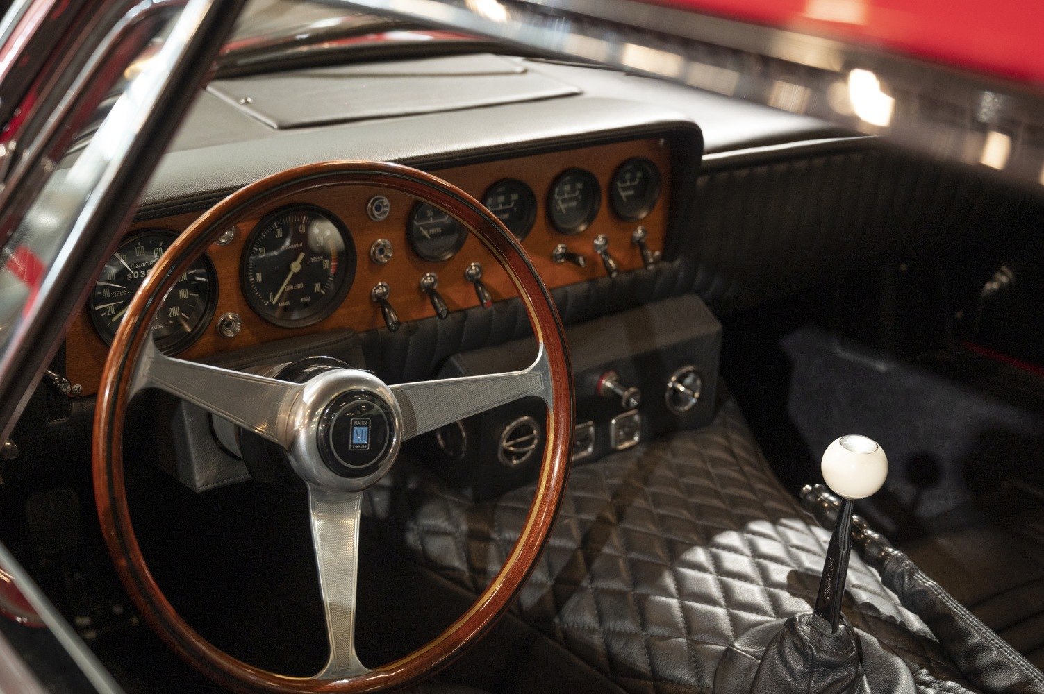 Vintage wood-trimmed steering wheel and quilted leather dashboard with gauges