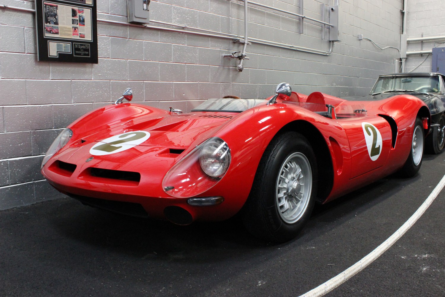 Red 1960s racing prototype with aerodynamic body and open cockpit
