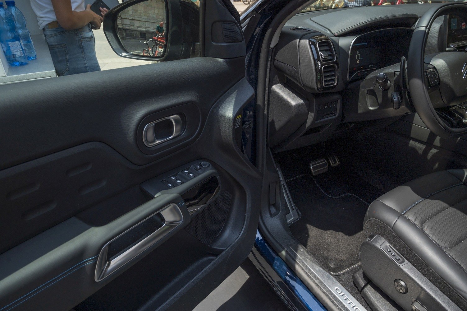 Close-up of car driver's door panel, seat controls, and dashboard interior details