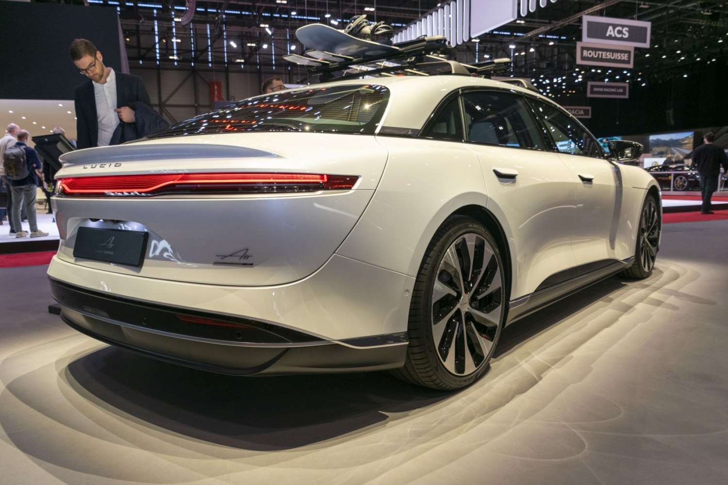Rear view of electric sedan with roof rack and surfboards