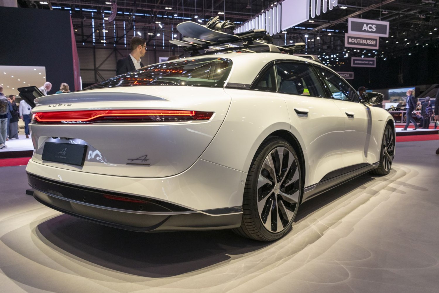 Rear view of electric sedan with LED tail lights and roof rack carrying a snowboard