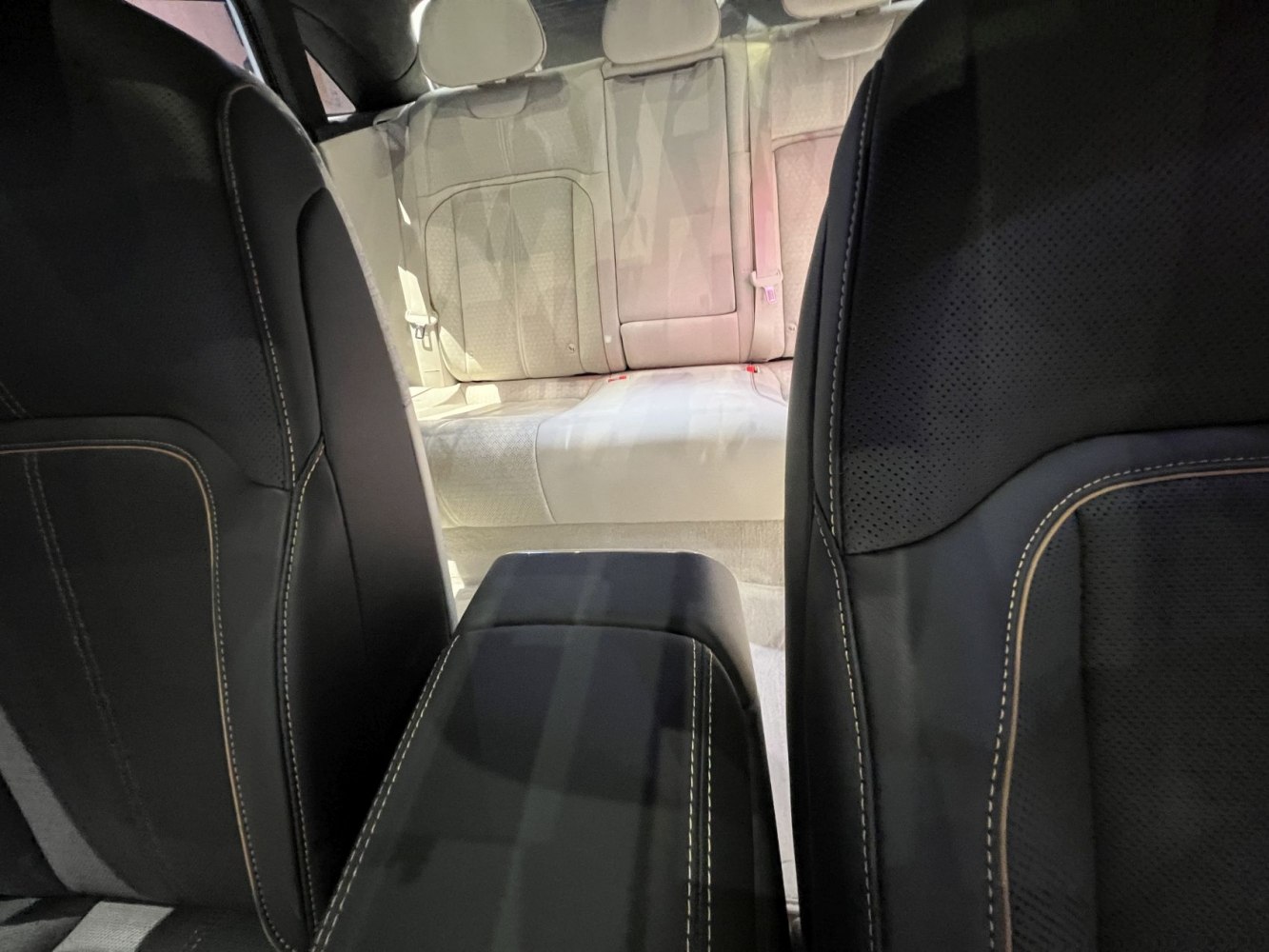 Black leather front seats and beige rear seating upholstery in a luxury car interior