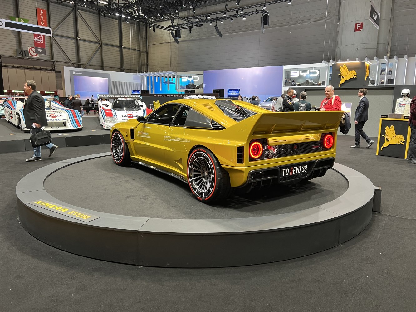 Large rear wing, round LED tail lights, yellow coupe on platform