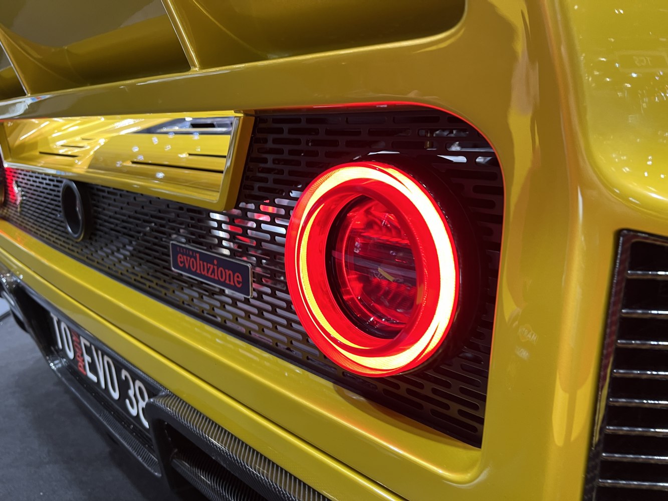 Illuminated circular tail light with black mesh grille on yellow rear panel