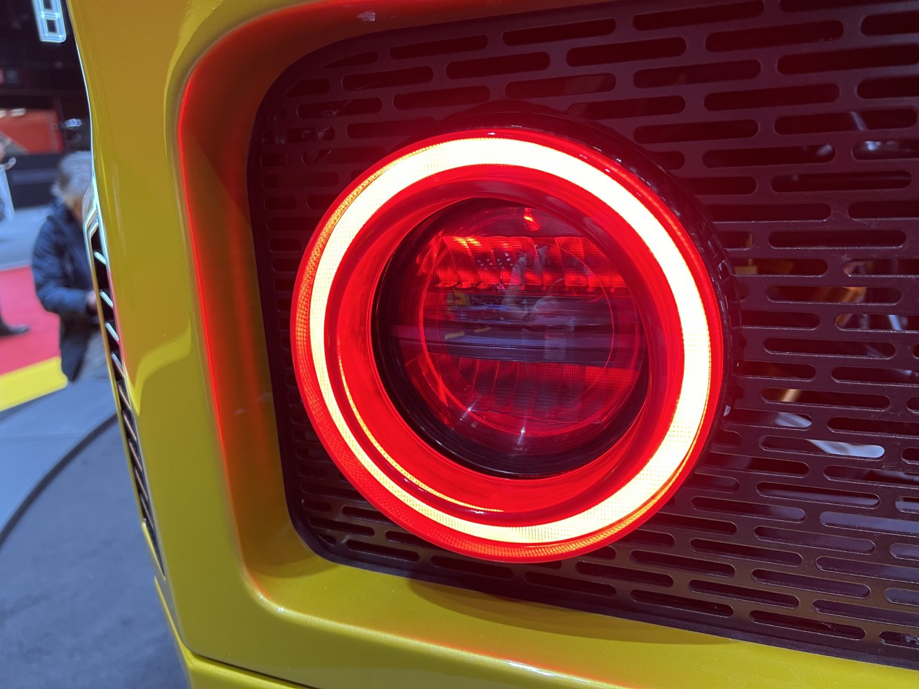 Circular LED rear light with distinctive red and white ring on yellow panel