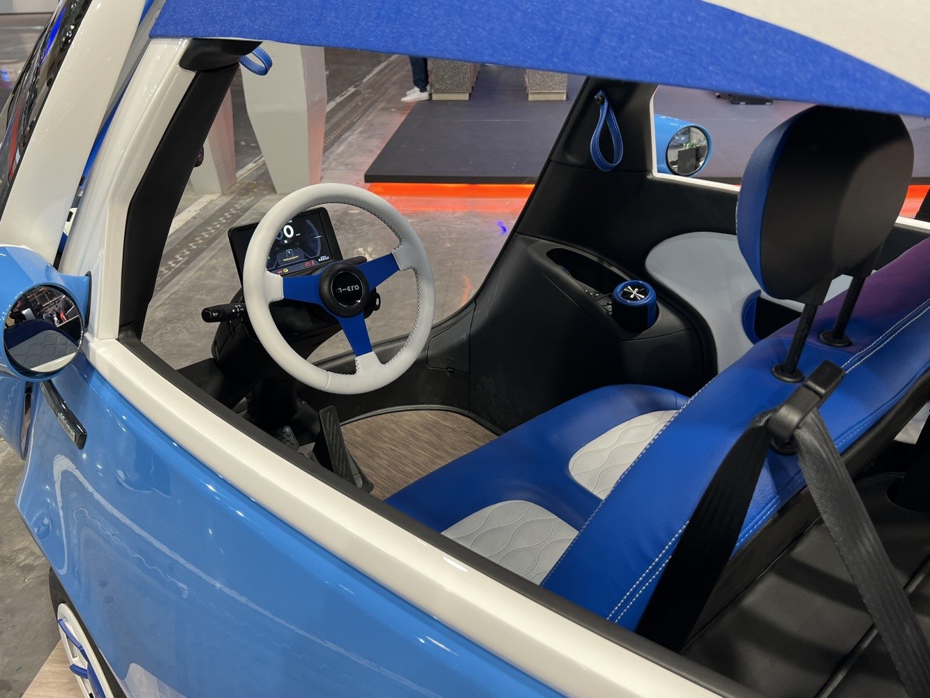 Compact modern electric vehicle interior with blue-white seats and digital dashboard