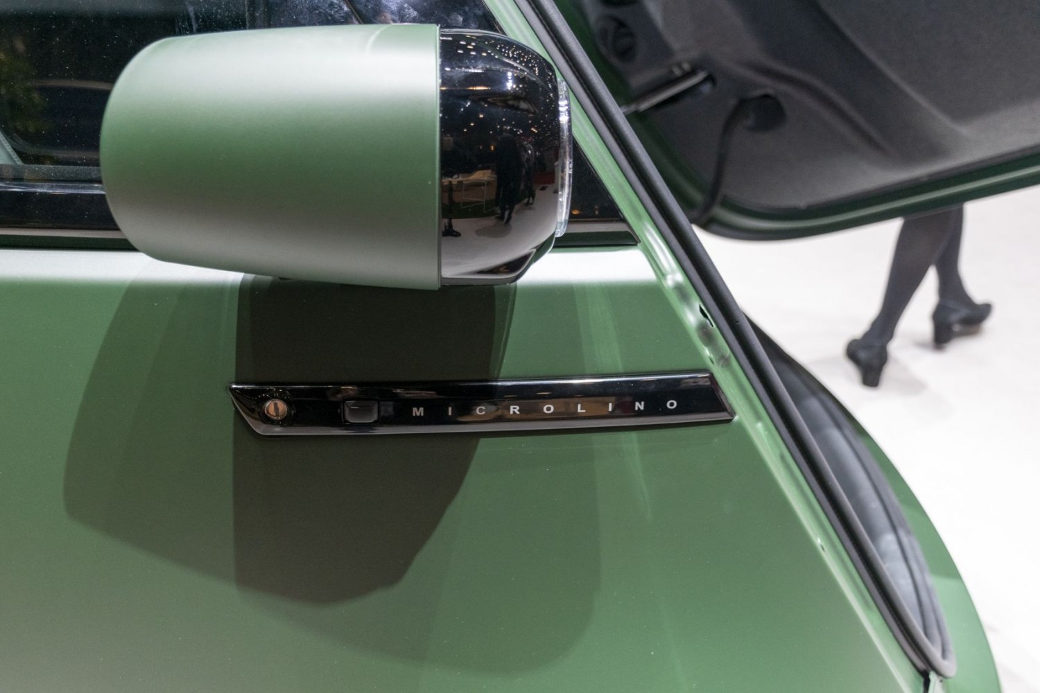 Green vehicle side mirror with Microlino emblem on door panel