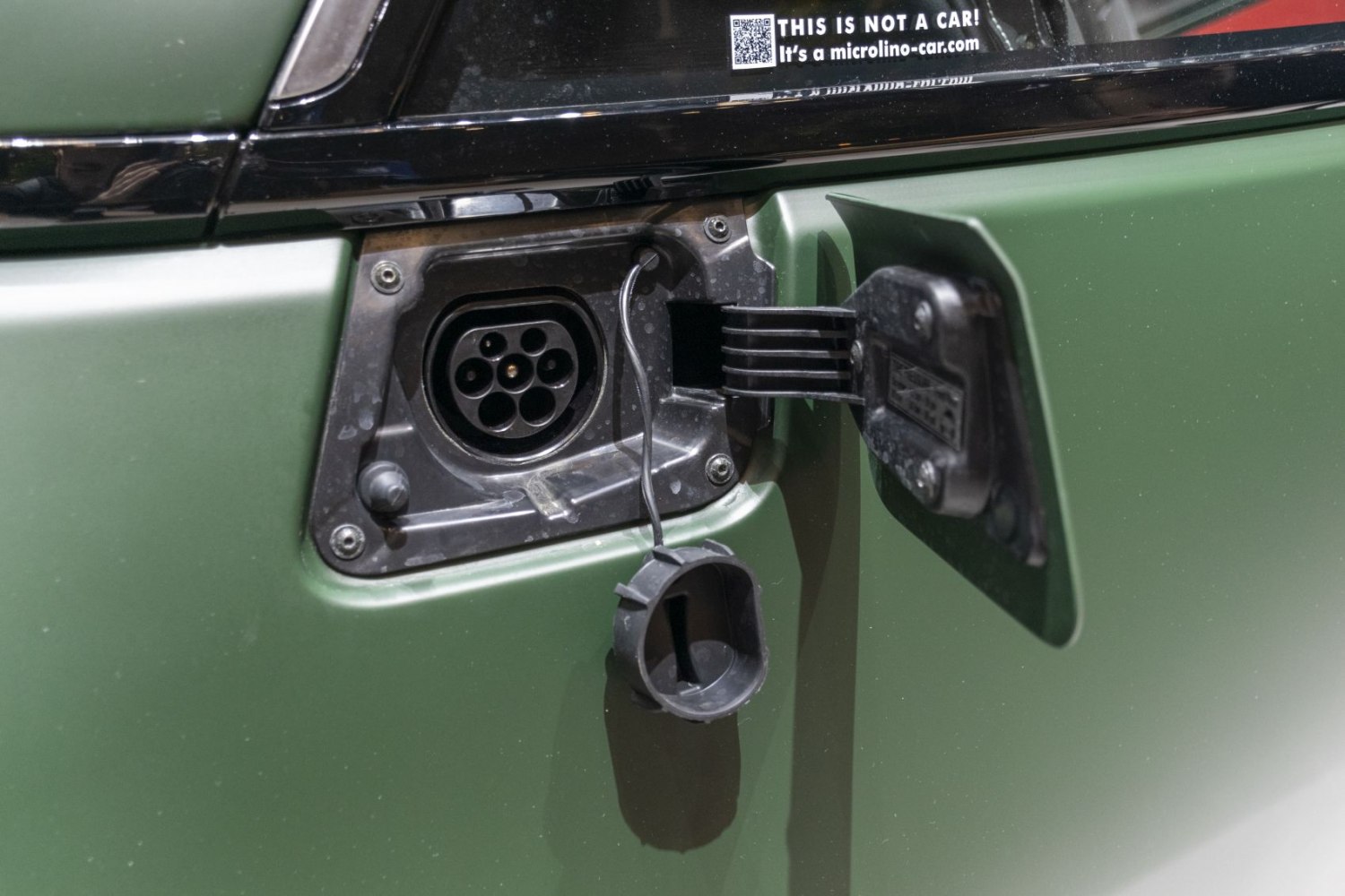 Close-up of electric vehicle charging port on green car body