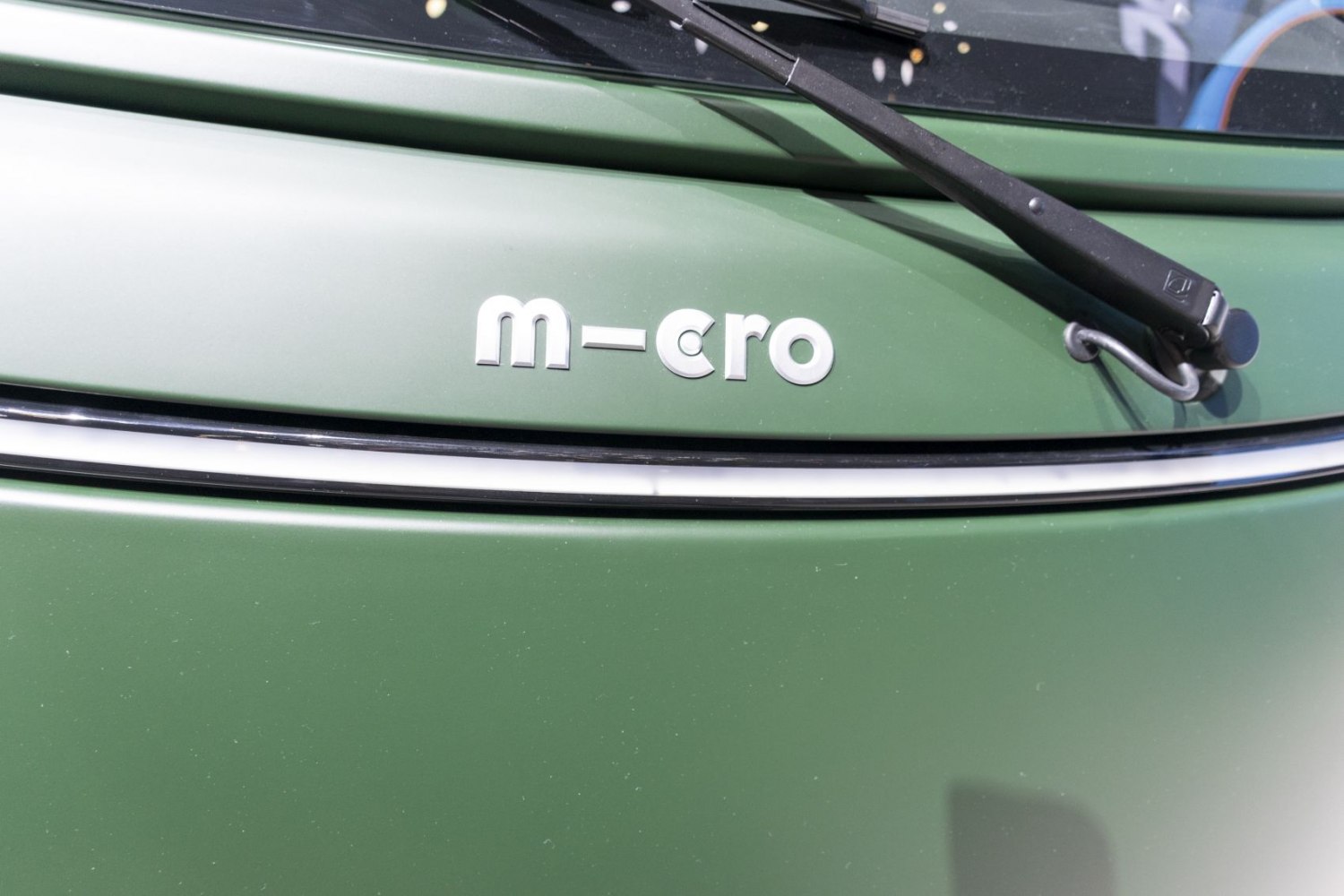 Close-up of vehicle front hood emblem and windshield wiper in green.