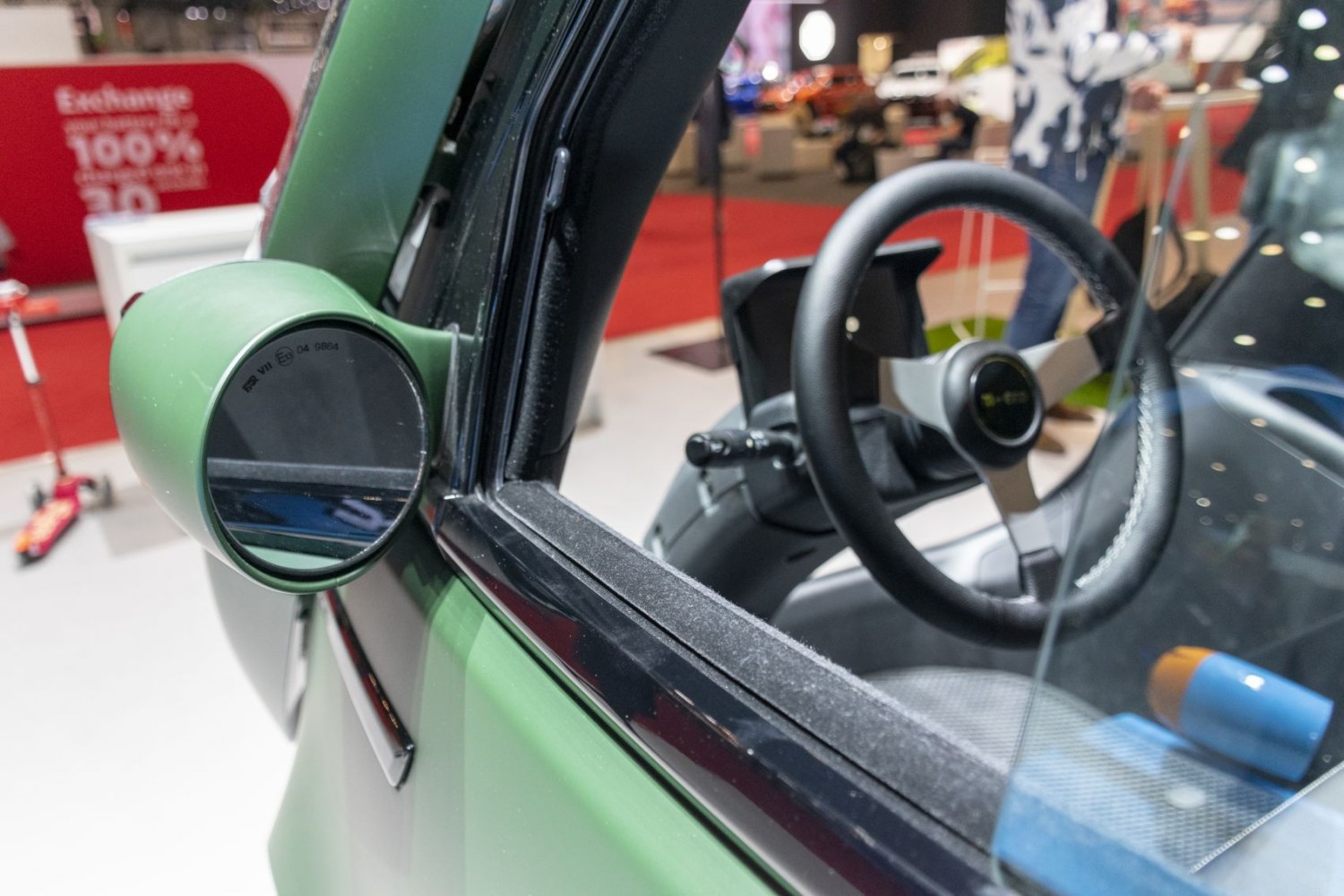 Side mirror and steering wheel close-up with green door frame