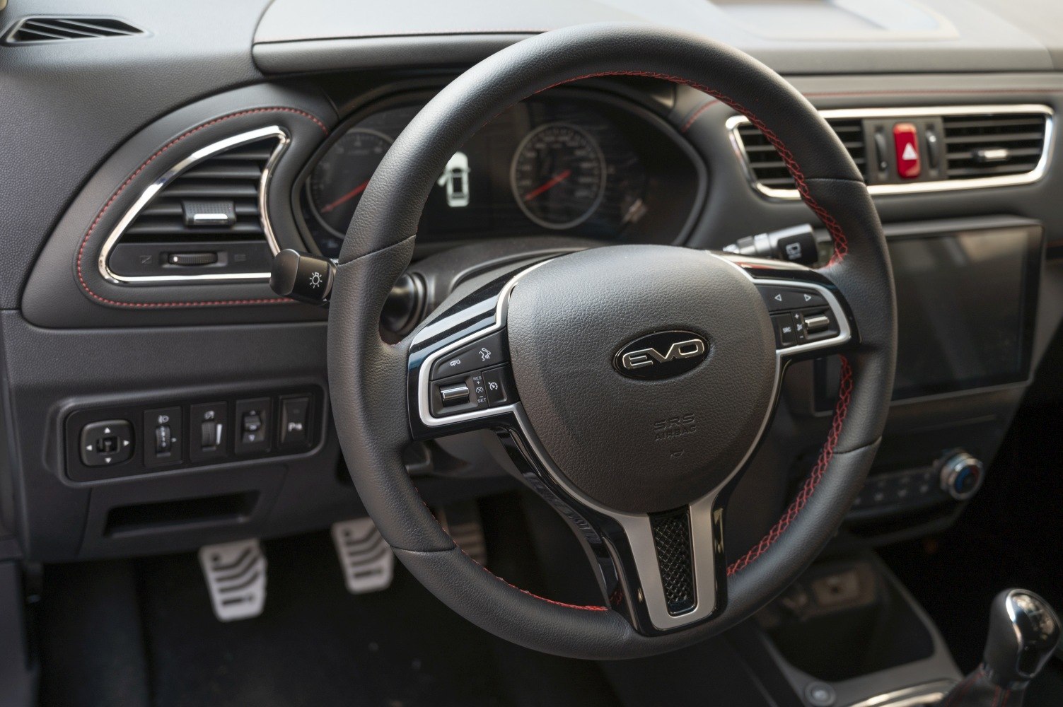 Steering wheel with red stitching and dashboard controls
