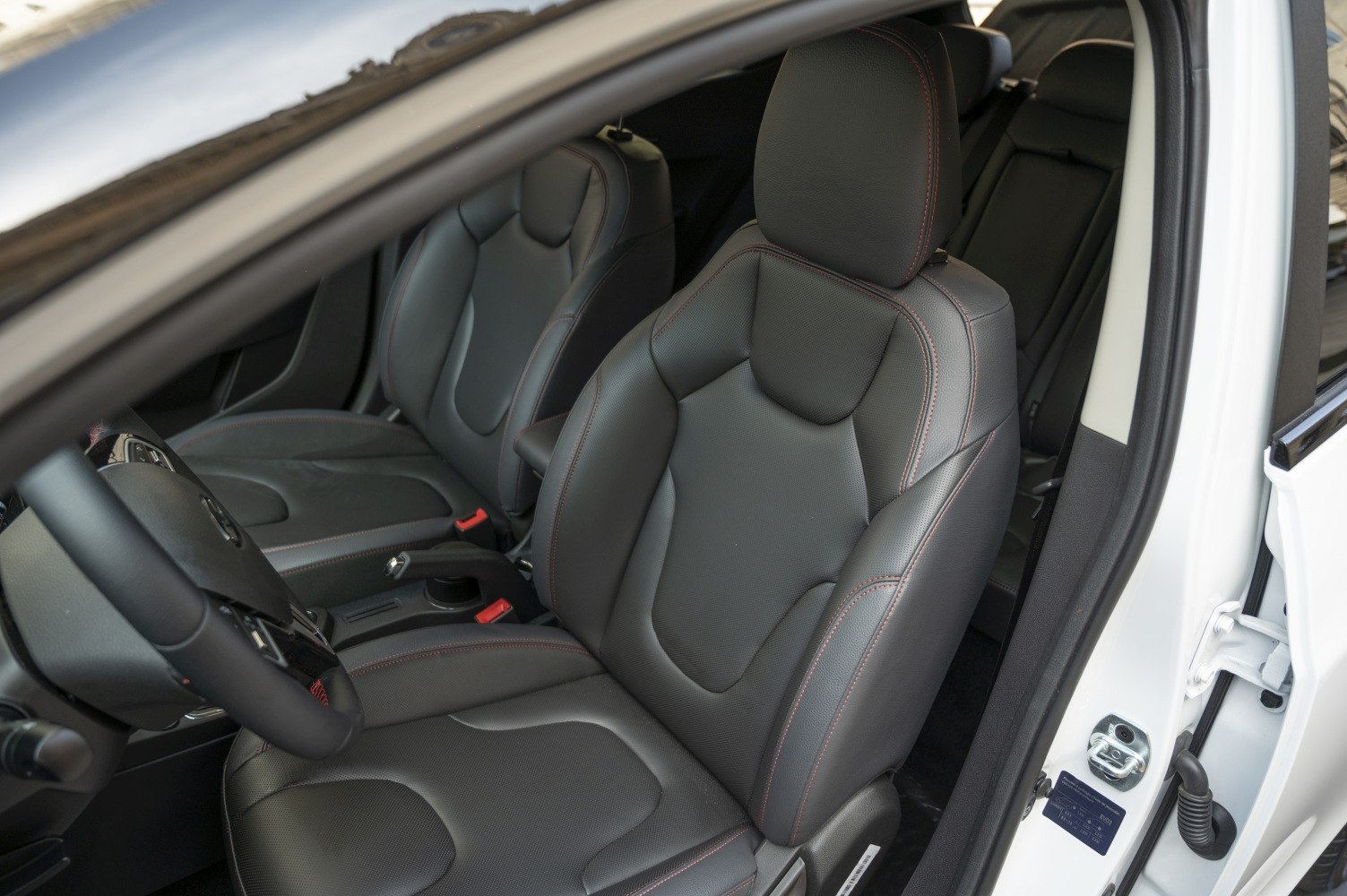 Black leather front seats with red stitching in vehicle interior