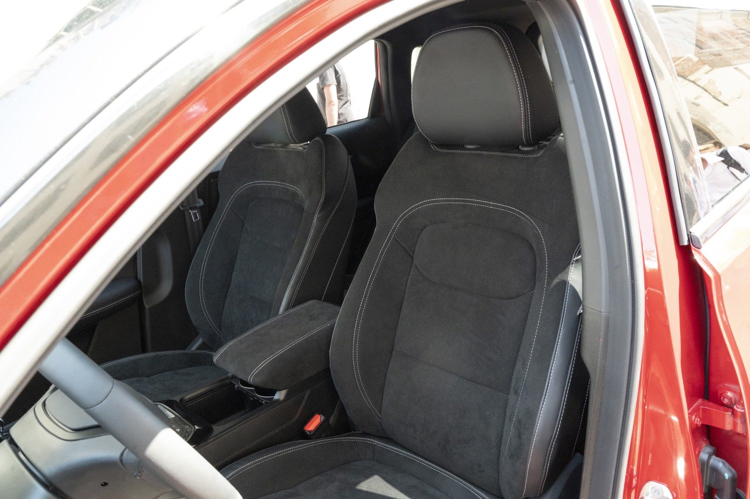 Black suede front seats with white stitching and central armrest