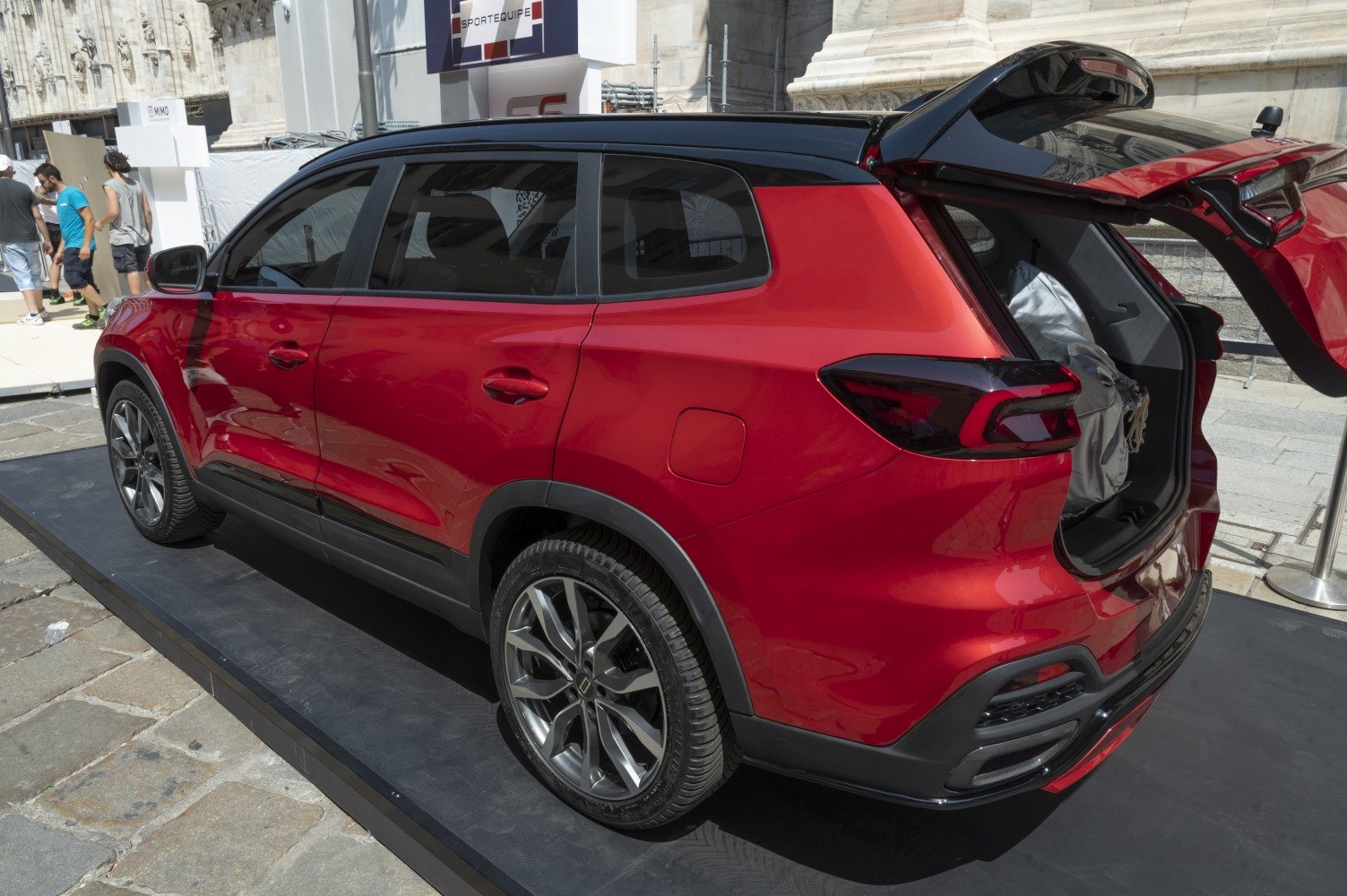 Rear-side view of red crossover SUV with open tailgate and alloy wheels