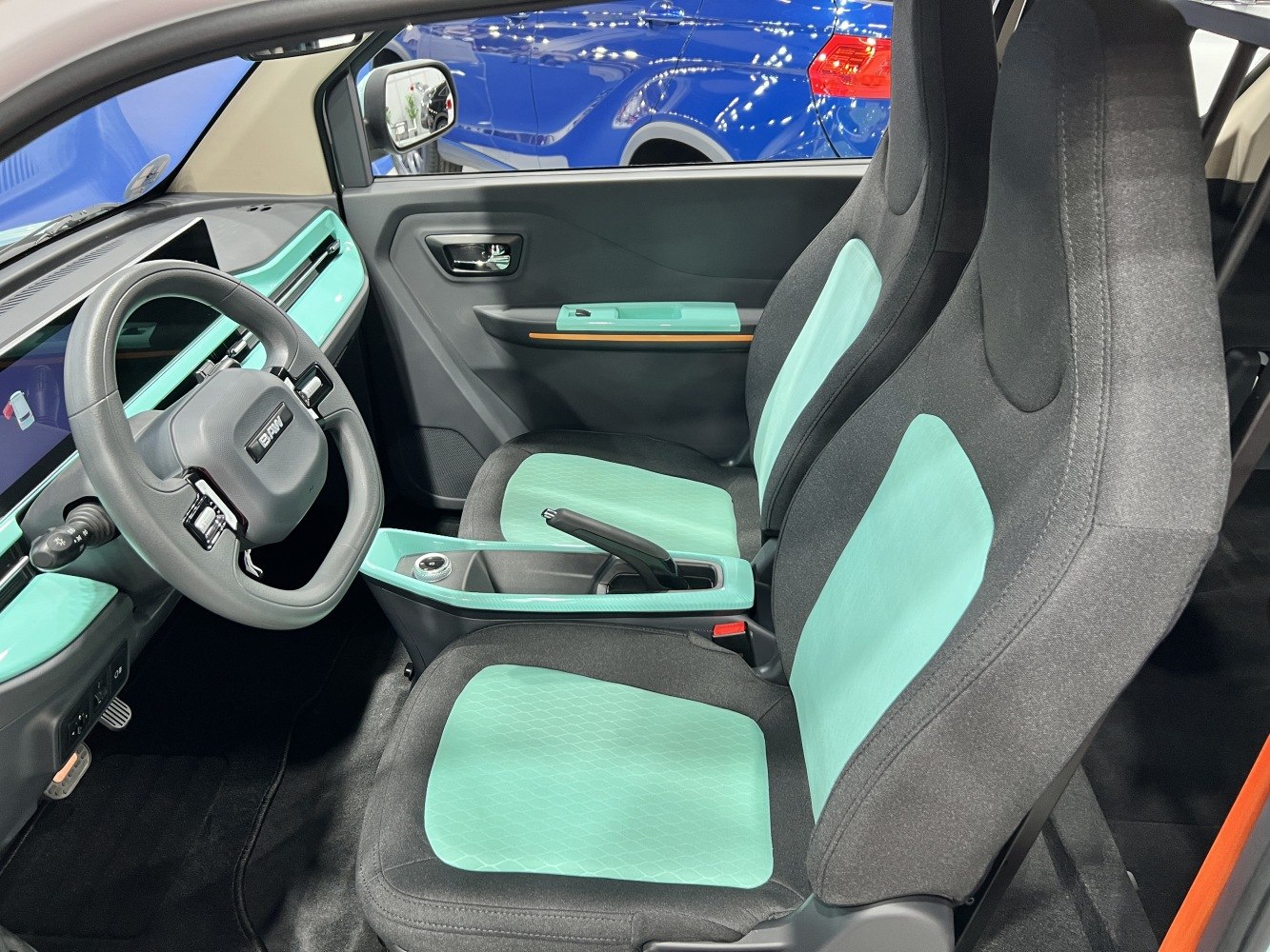 Modern car interior with digital dashboard and turquoise-accented seats.