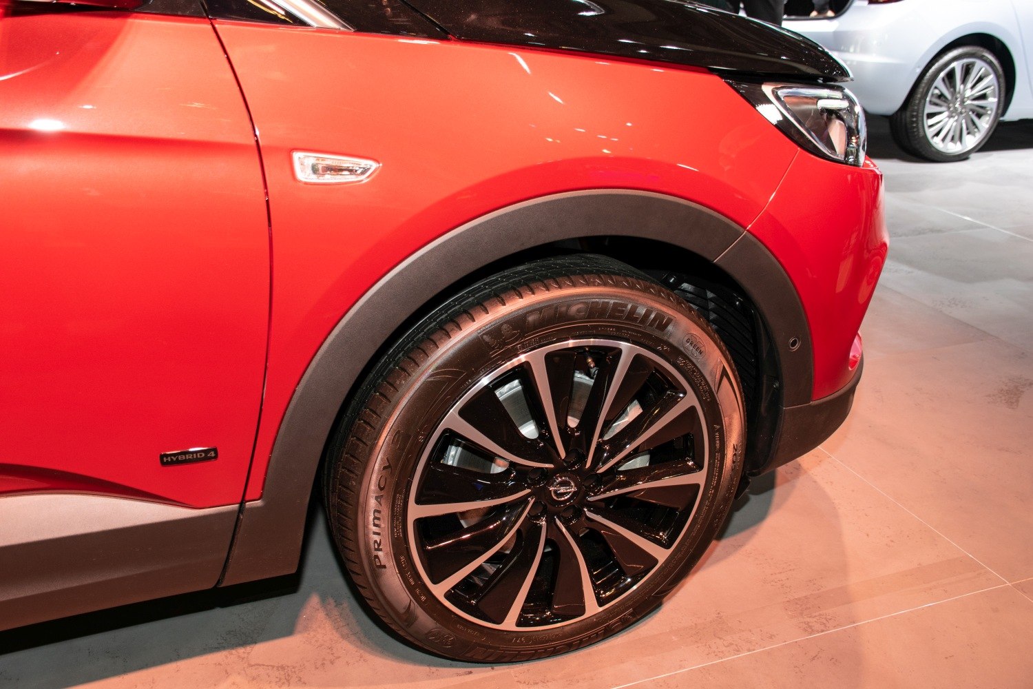 Front wheel with Michelin tire and stylish alloy rim on red SUV.