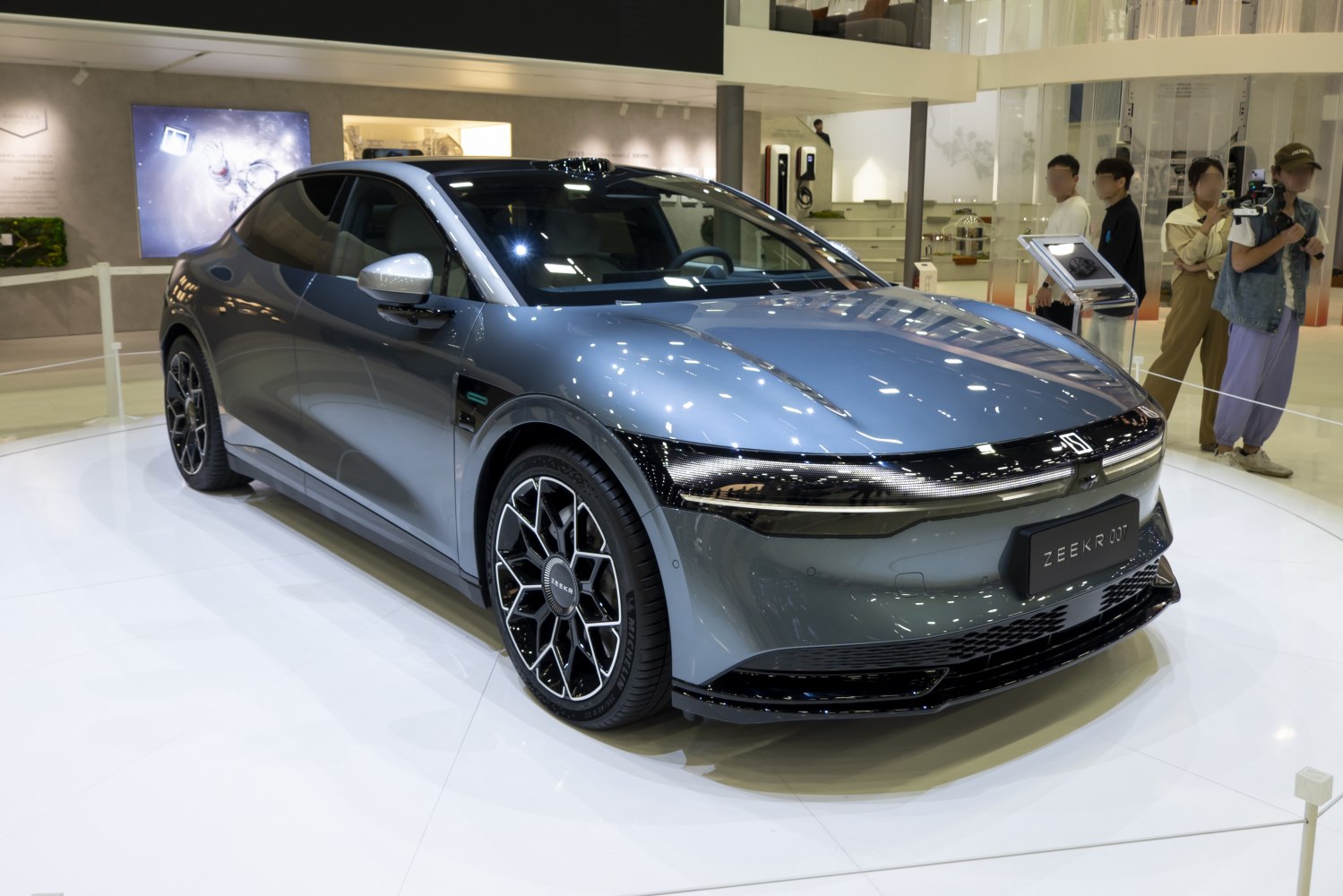 Electric sedan with full-width LED headlights and multi-spoke alloy wheels