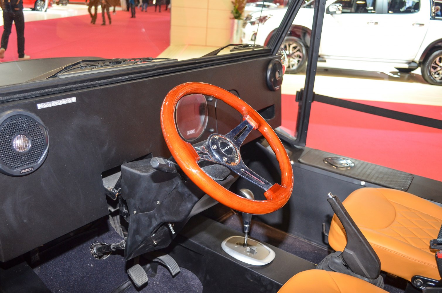 Wooden steering wheel, black dashboard, orange seats in electric vehicle interior